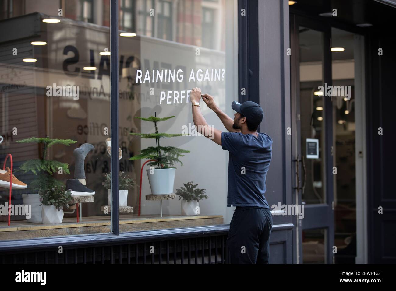 Un lavoratore prepara una vetrina come non-essenziale negozi sulla strada alta sono pronti per riaprire dopo il blocco britannico coronavirus è rilassato, Londra, Regno Unito Foto Stock