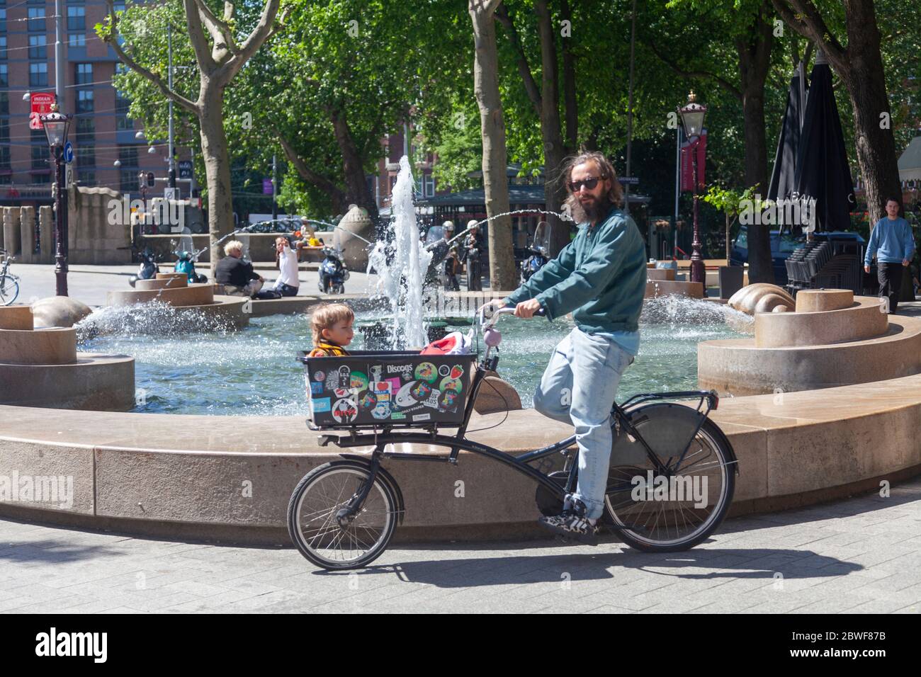 Un padre cavalcare una bicicletta con cesto per il suo bambino, Amsterdam Foto Stock