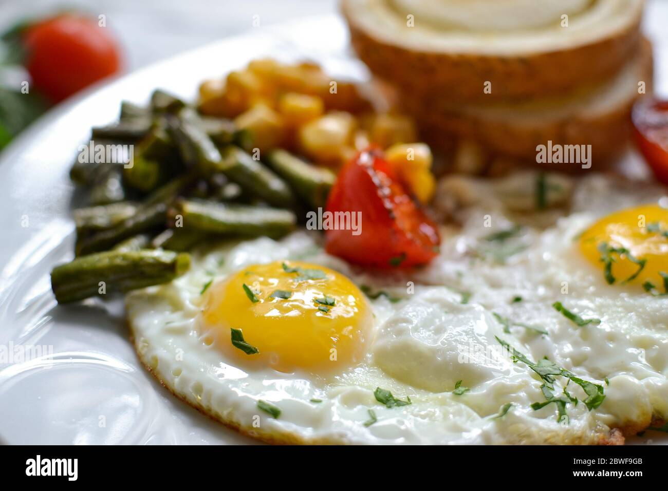 Uova fritte con pomodori, fagioli verdi, mais e pane tostato. Colazione inglese vegetariana. Primo piano con caffè e uova fritte. Foto Stock