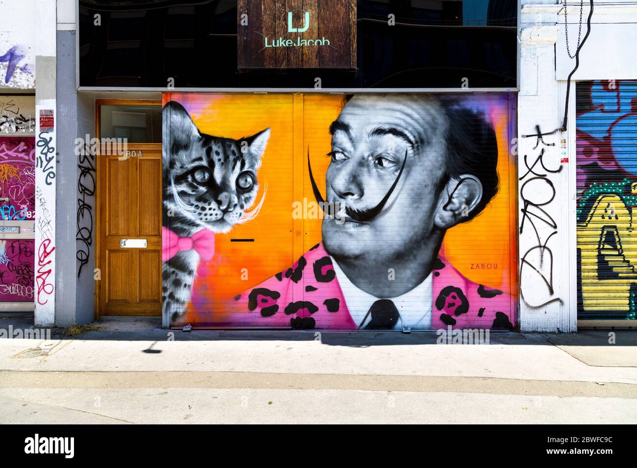 Murale di artisti Salvador Dail con baffi rovesciati e un gatto con arco rosa di Zabou, Spitalfields, Londra, UK Foto Stock