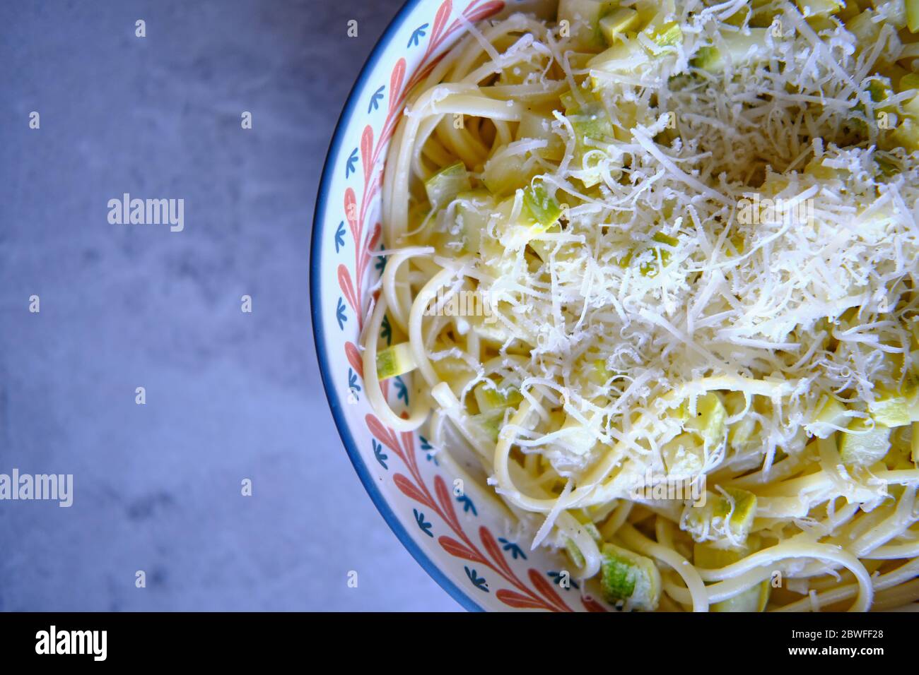 Spaghetti di pasta con zucchine, basilico e parmigiano su tavola di marmo bianco. Pasta vegetale vegetariana. Tagliatelle di zucchine. Vista dall'alto. Foto Stock