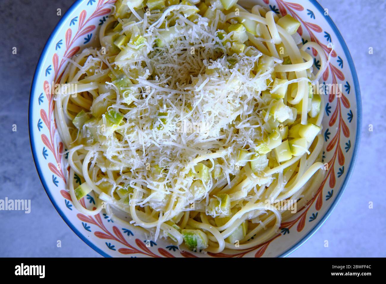 Spaghetti di pasta con zucchine, basilico e parmigiano su tavola di marmo bianco. Pasta vegetale vegetariana. Tagliatelle di zucchine. Vista dall'alto. Foto Stock