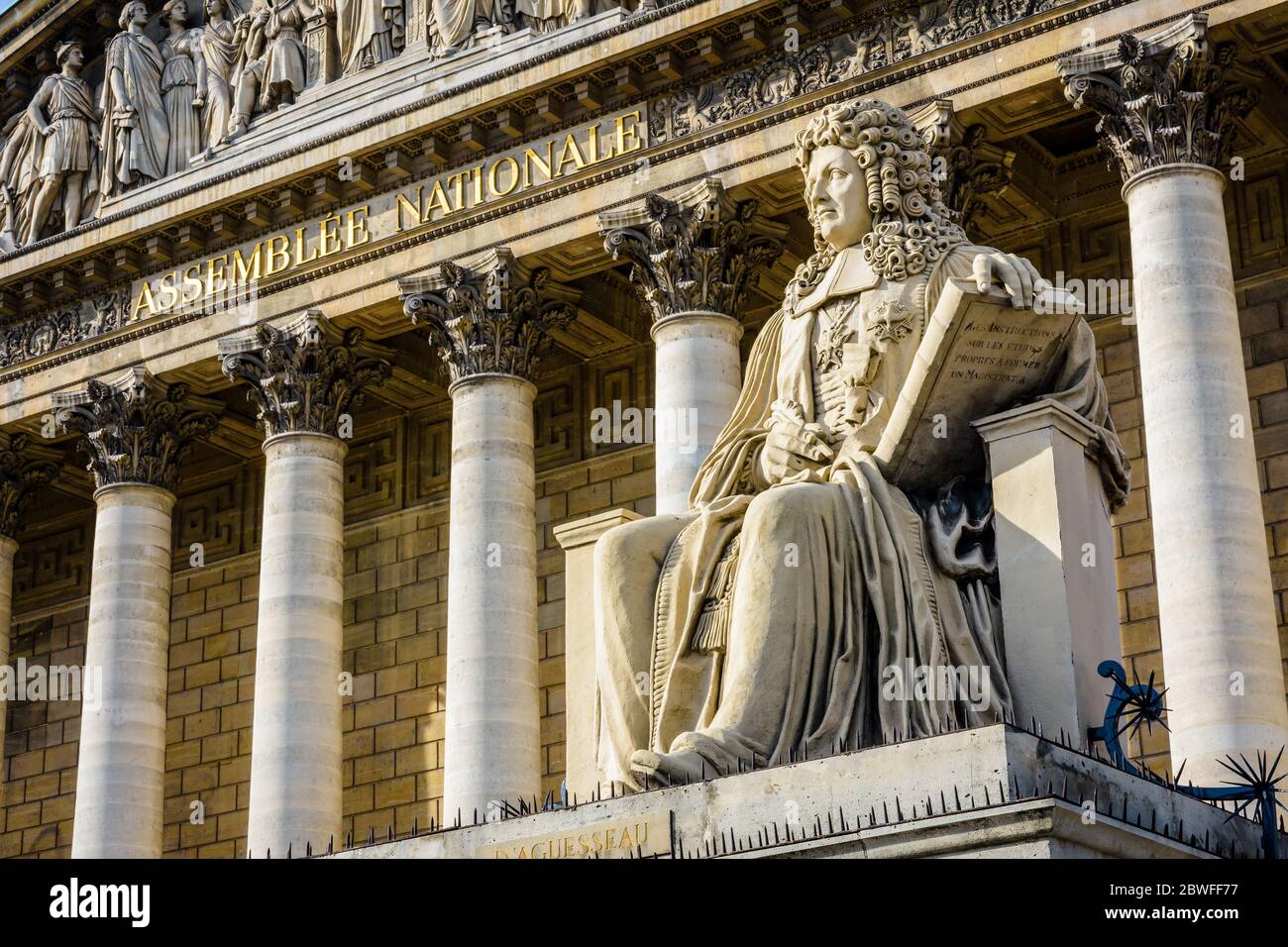 Vista ad angolo basso della statua di Francois d'Aguesseau di fronte alla facciata neoclassica del Palais Bourbon, sede dell'Assemblea nazionale francese i Foto Stock