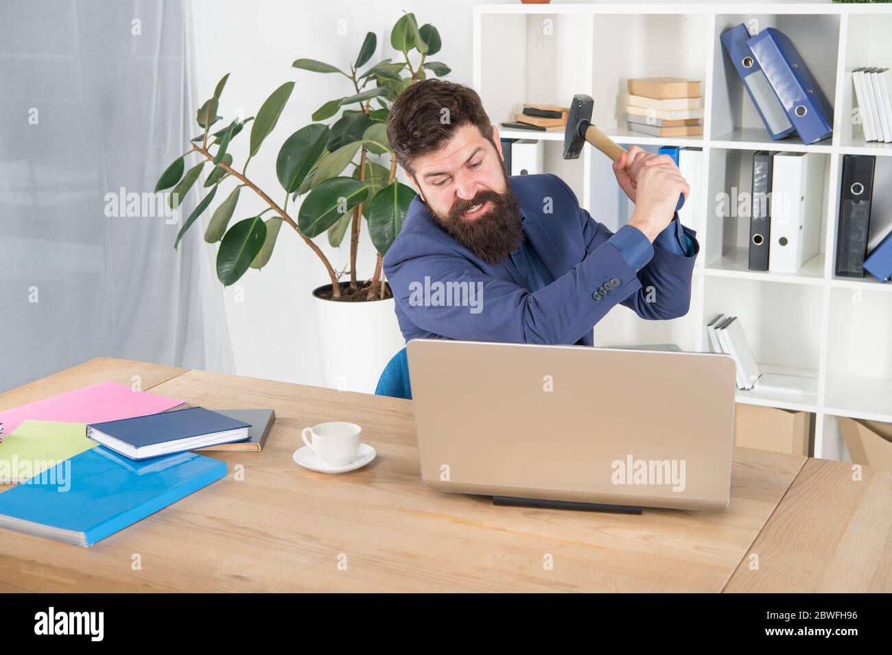 odio il mio lavoro. trattare con errore. uomo in eccesso schiacciare il laptop con martello. frustrato utente del computer. uomo d'affari esprimere rabbia. pronto a battere. La vita in ufficio lo rende pazzo. Connessione Internet lenta. Foto Stock