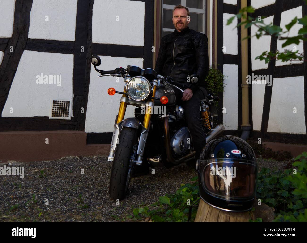 Bicker in jaket nero sulla sua moto Foto Stock