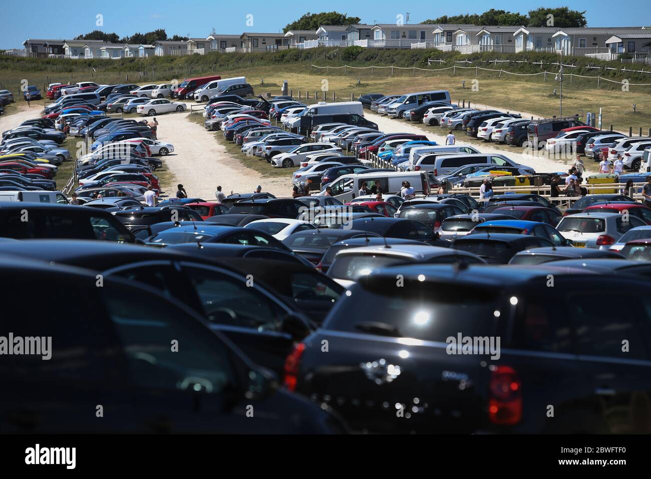 Il parcheggio principale (sfondo) e il parcheggio per auto di troppo pieno (primo piano) a Duddle Door, vicino a Lulworth, in Dorset, dopo che il pubblico è stato ricordato di praticare la distanza sociale a seguito del rilassamento delle restrizioni di blocco coronavirus in Inghilterra. Foto Stock