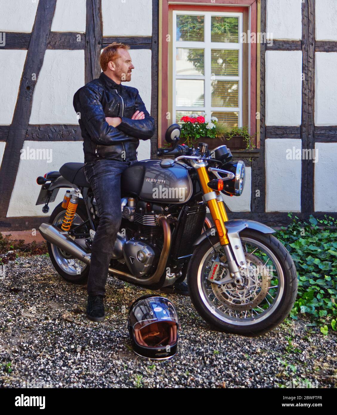 Bicker in jaket nero sulla sua moto Foto Stock