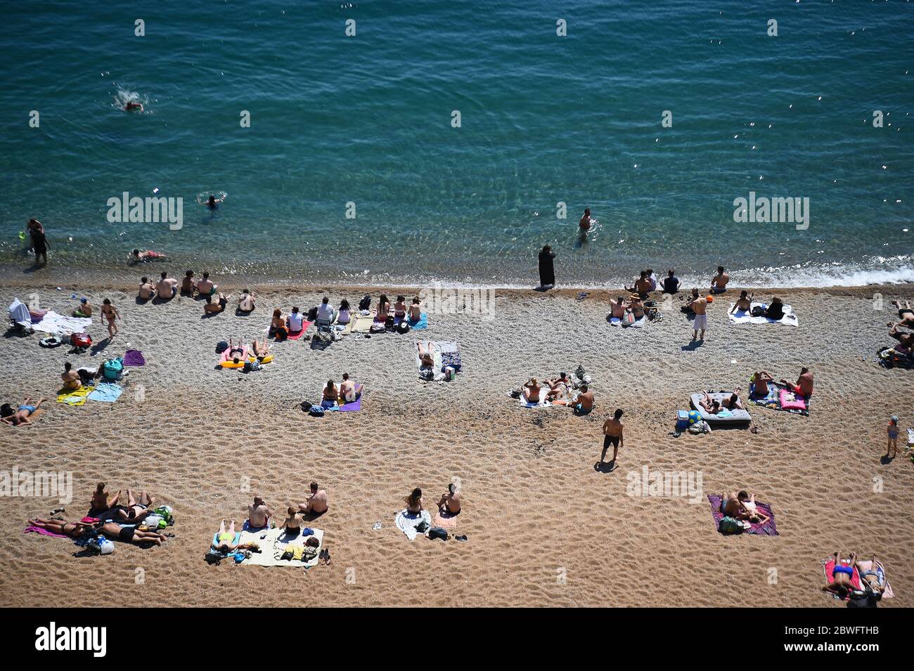 La gente gode il tempo caldo sulla spiaggia a Dudle Door, vicino a Lulworth, in Dorset, dopo che il pubblico è stato ricordato di praticare l'allontanamento sociale a seguito del rilassamento delle restrizioni di blocco del coronavirus in Inghilterra. Foto Stock