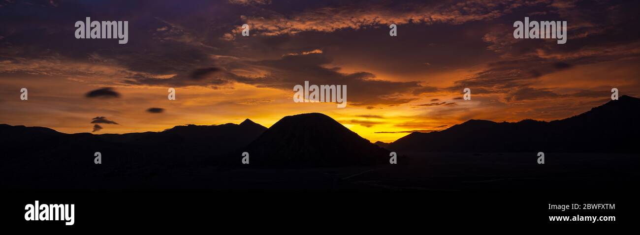 Incredibile drammatico tramonto dietro la silhouette della gamma della montagna che include il Monte Semeru, Monte Batok e Monte Bromo in Java Orientale, Indonesia. Foto Stock