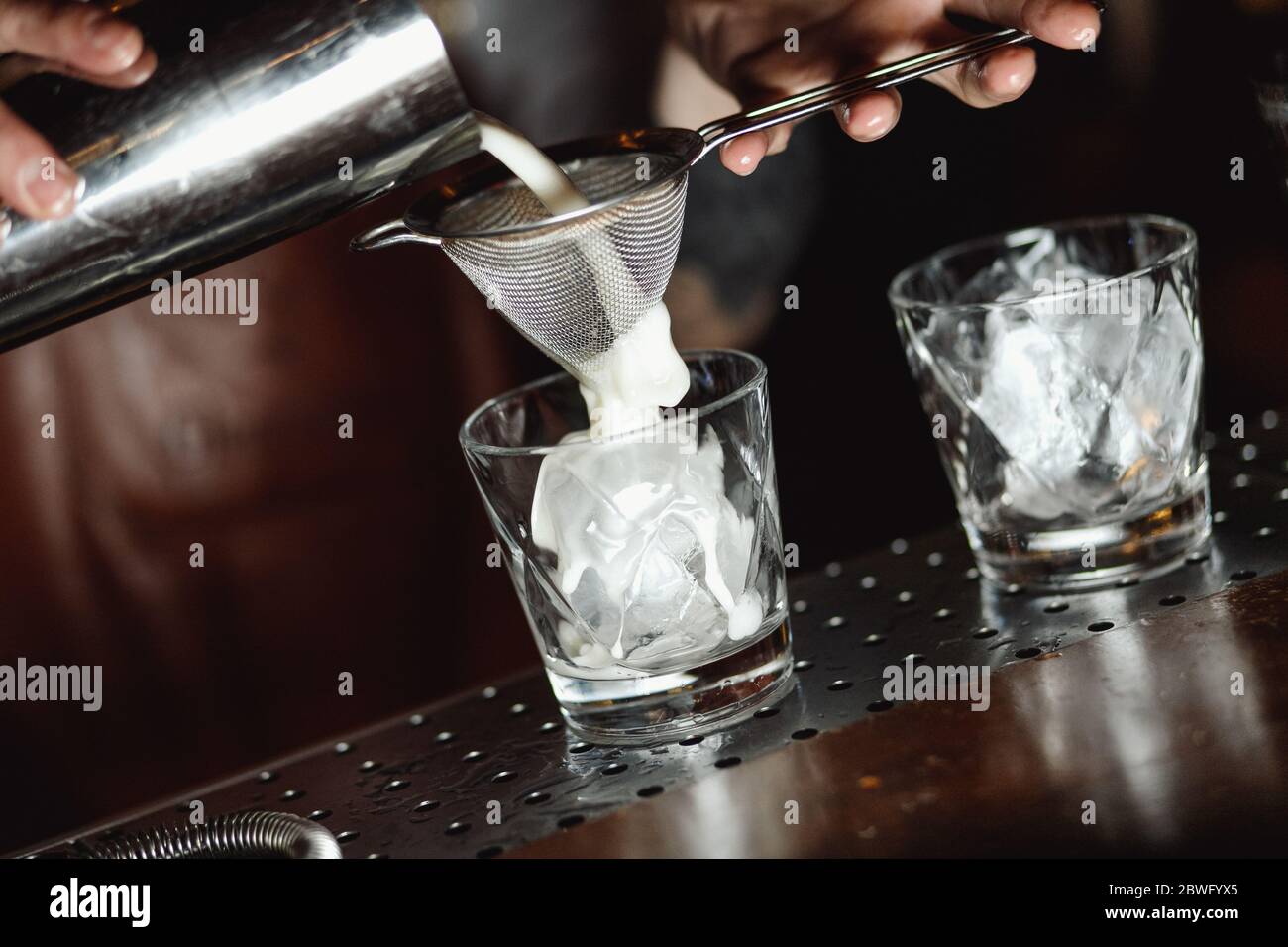 La crema viene aggiunta ad un bicchiere di cocktail russo bianco Foto Stock