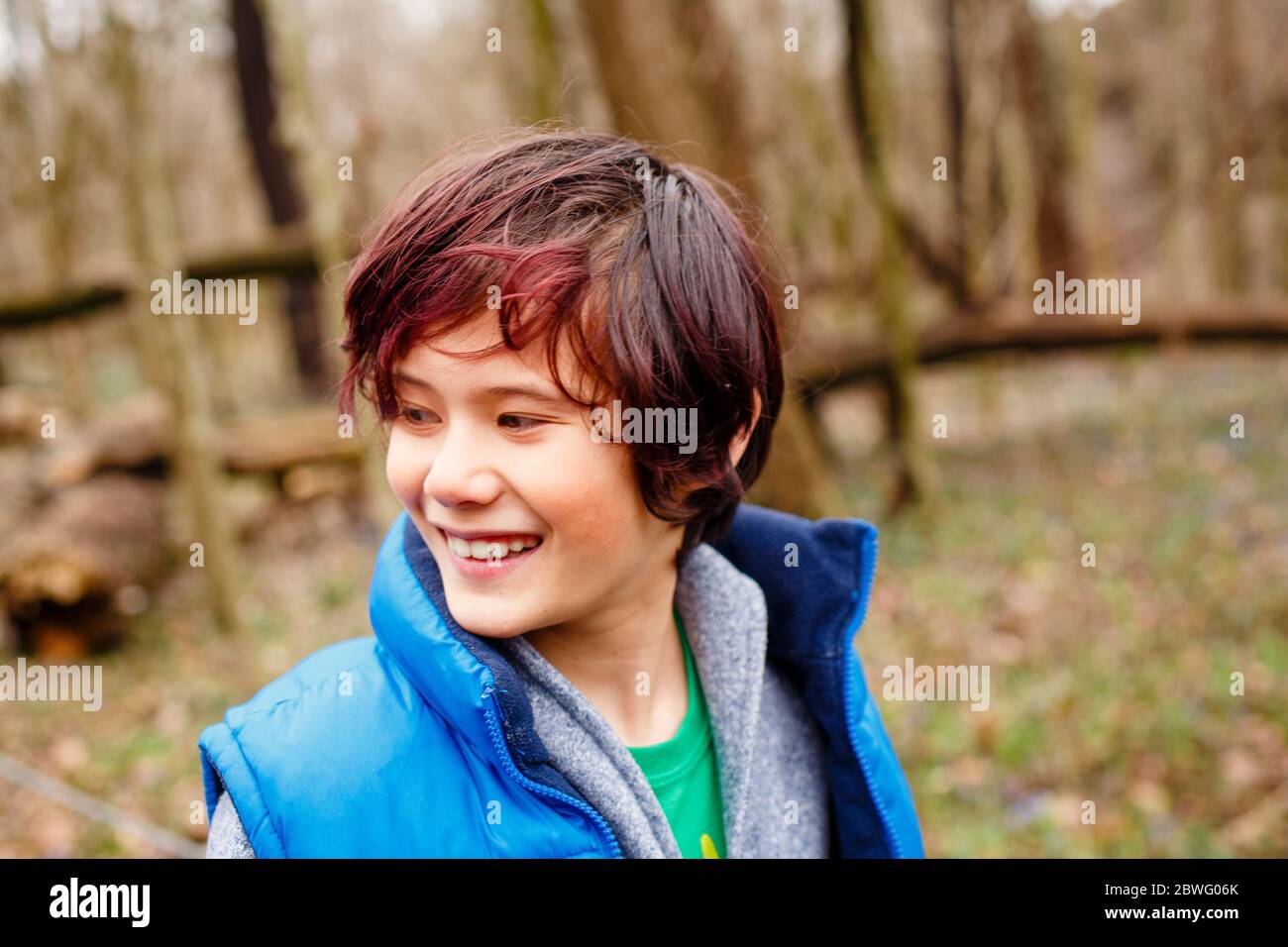Un ragazzo sorridente guarda da parte mentre si è in piedi In boschi in primavera Foto Stock
