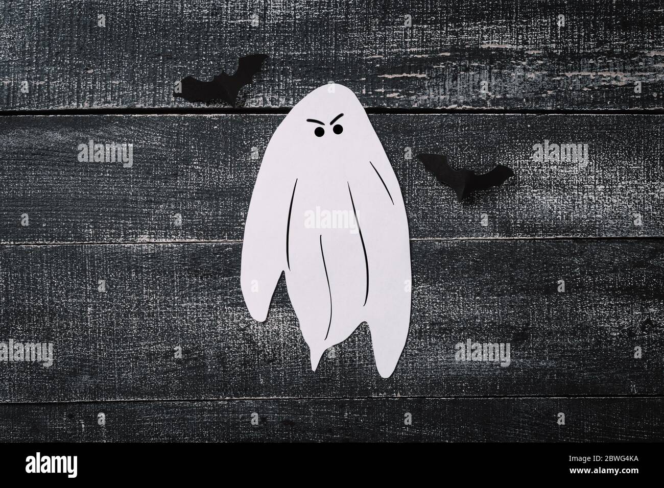 Costume fantasma bianco su sfondo nero scuro di legno. Concetto minimalista di Halloween. Carta tecnica fantasma Foto Stock