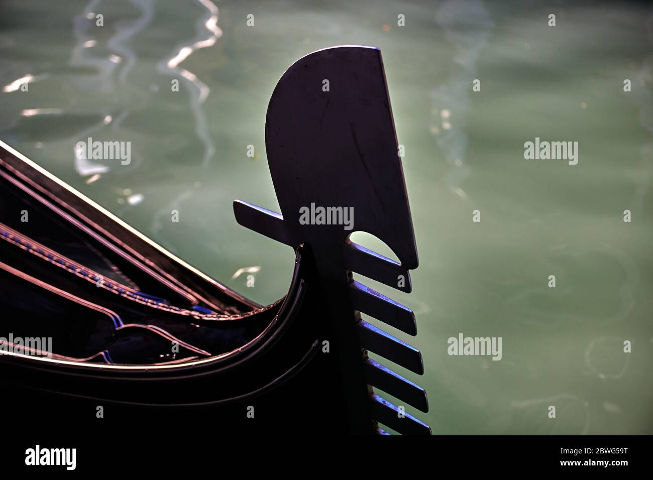 Primo piano sulla prua di una gondola a Venezia, lungo il canale di acqua di mare, in una soleggiata giornata invernale. Concentrarsi solo sul prow. Foto Stock