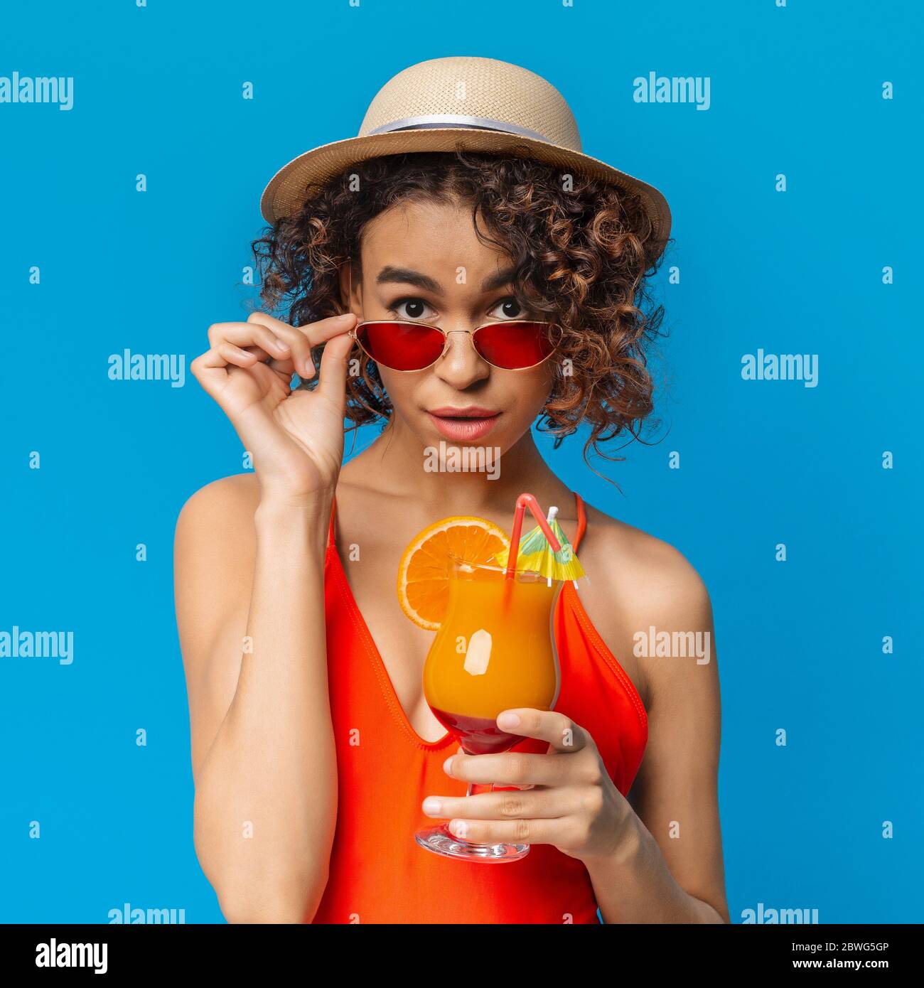 Bella ragazza nera in abiti estivi alla moda in posa con cocktail di frutta Colorfu Foto Stock