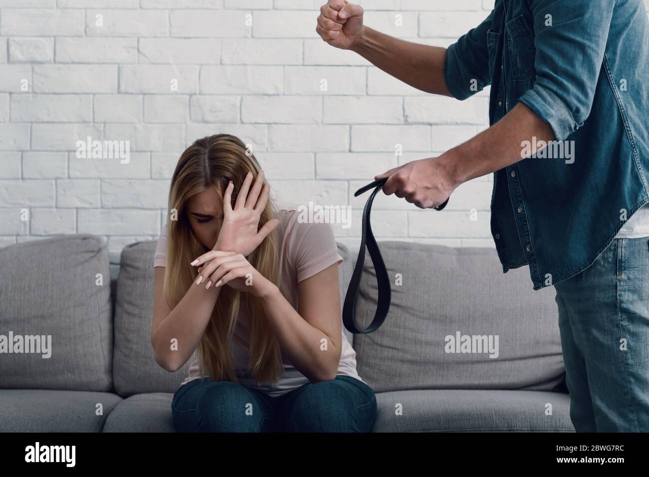Battere e umiliazione. L'uomo minaccia con pugno alla donna, chiude il viso con le mani Foto Stock