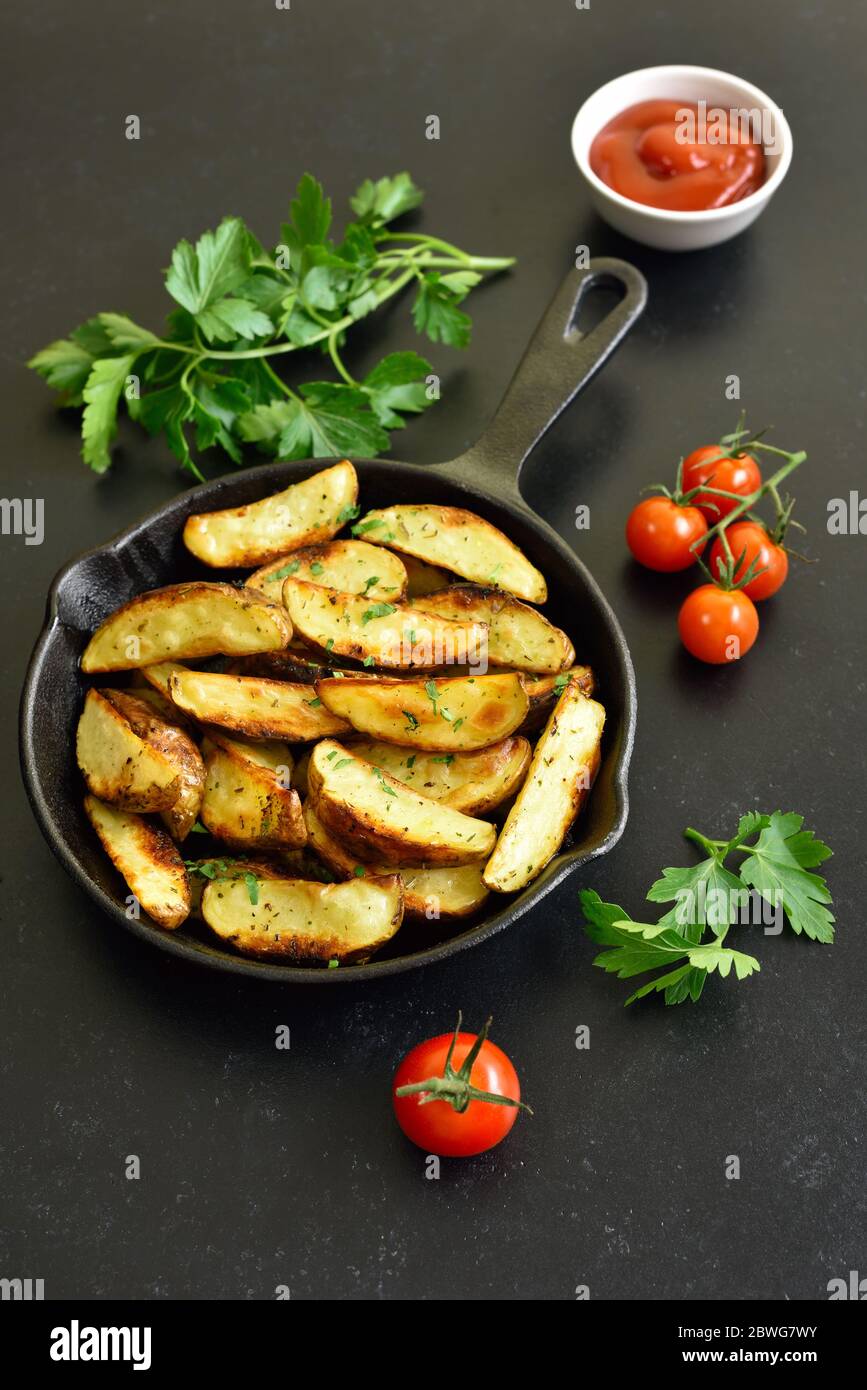 Fette di patate fritte in padella su fondo di pietra nera Foto Stock