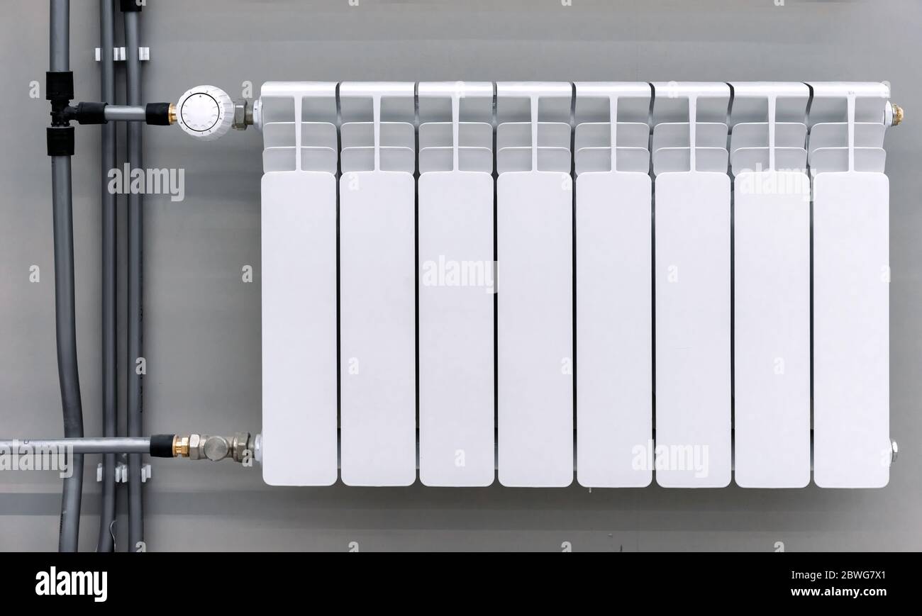 Radiatore bianco con valvola di regolazione della temperatura. Batteria riscaldamento centralizzato. Foto Stock