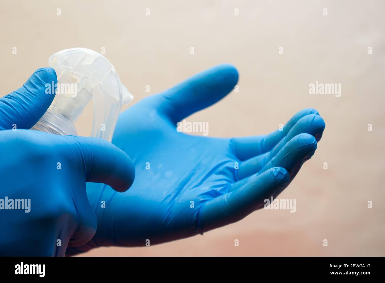 Mani in guanti medici maneggiare uno spray con un antisettico alcol - protezione contro l'influenza durante la quarantena, coronavirus, covid19 Foto Stock