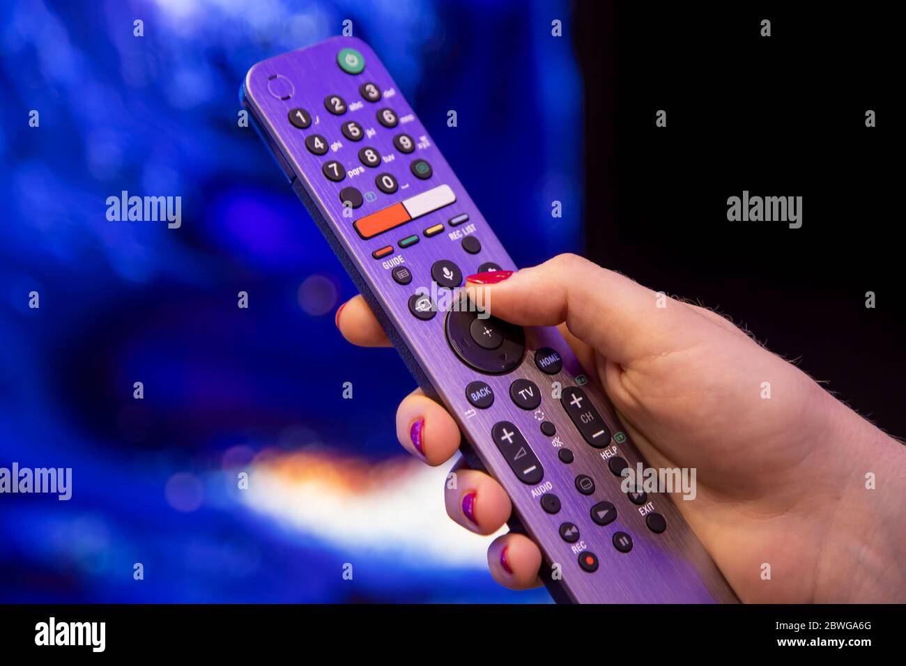 La mano femminile tiene un telecomando per Smart TV con microfono e comando vocale. Foto Stock
