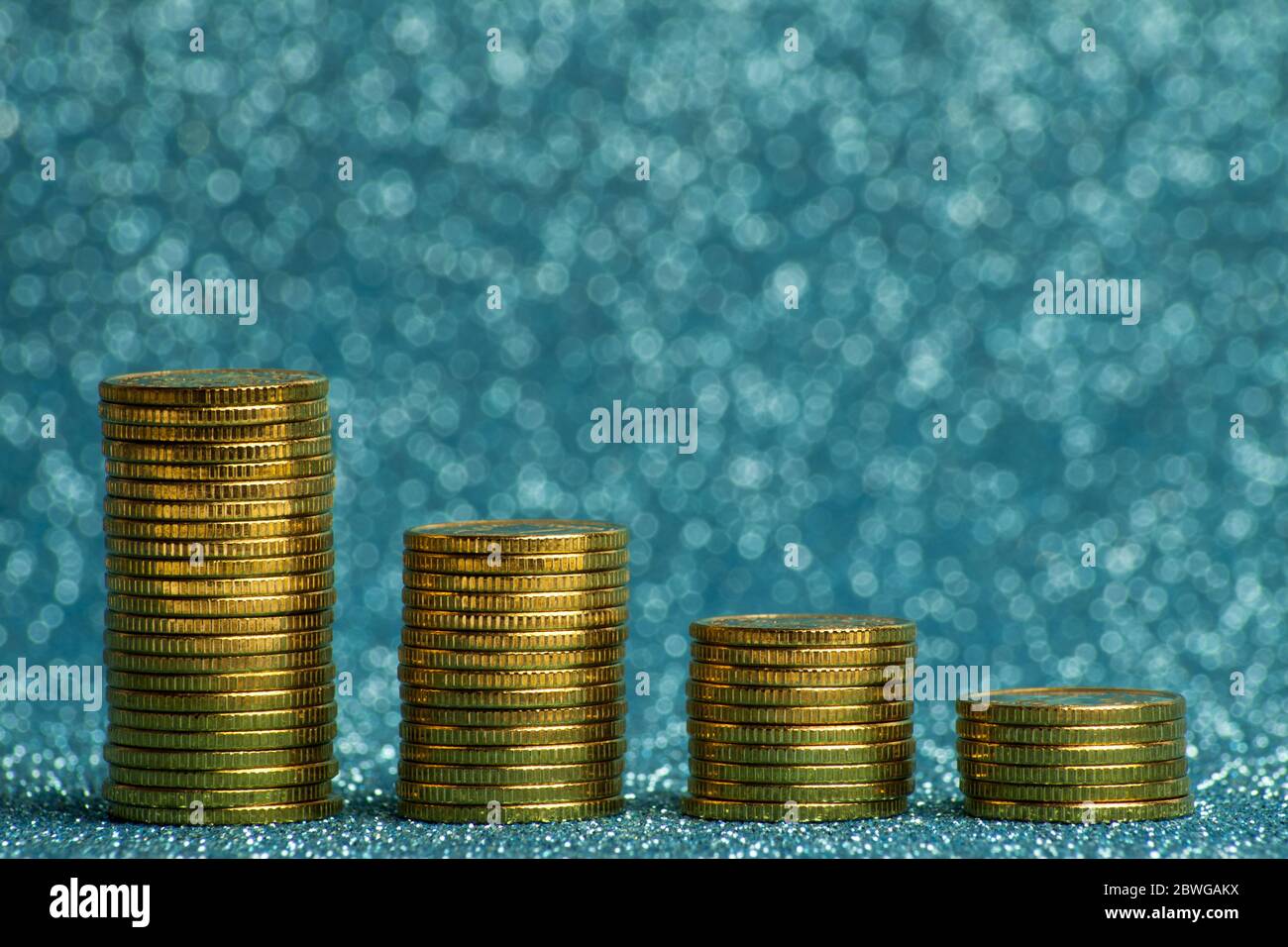 Piramide di pile di monete d'oro su sfondo blu. Foto Stock