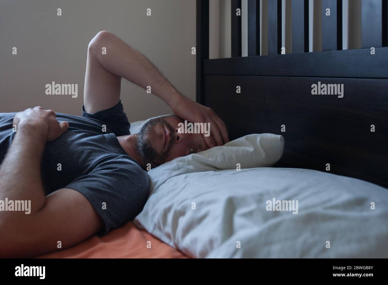 Uomo che guarda infelice a letto Foto Stock