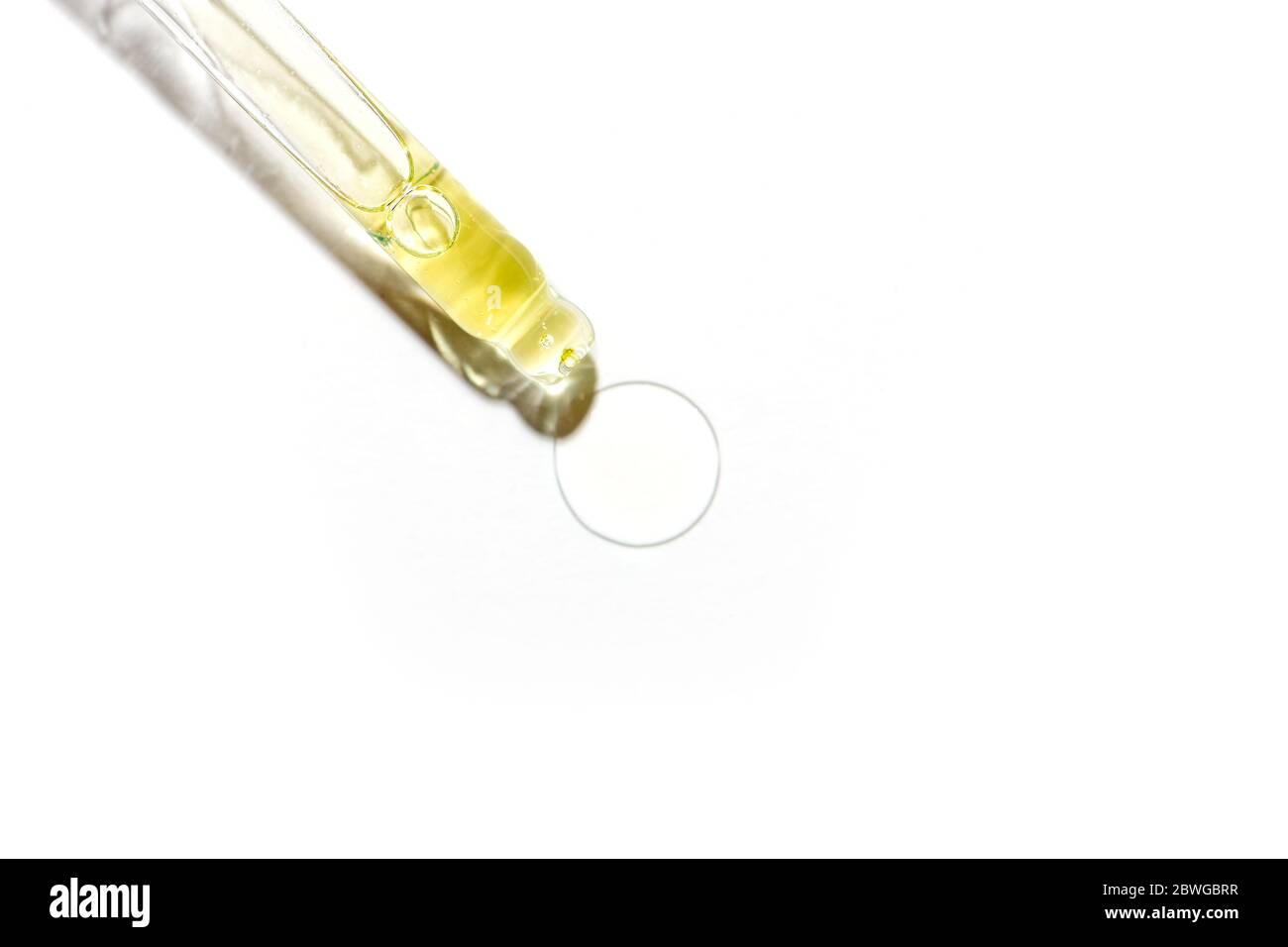 Pipetta in vetro trasparente con olio su bianco. Foto Stock