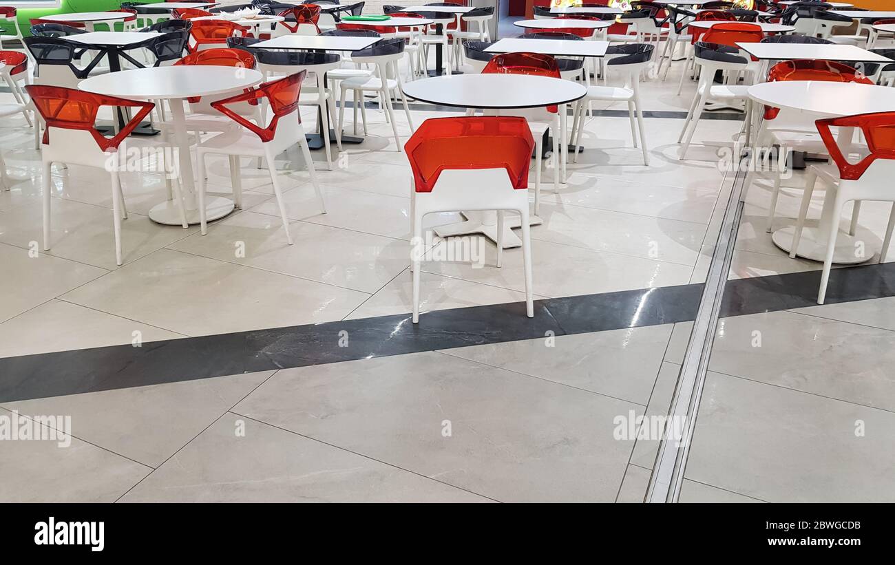 area ristorazione con tavoli e sedie in plastica bianca e rossa in un centro commerciale senza persone. Foto Stock