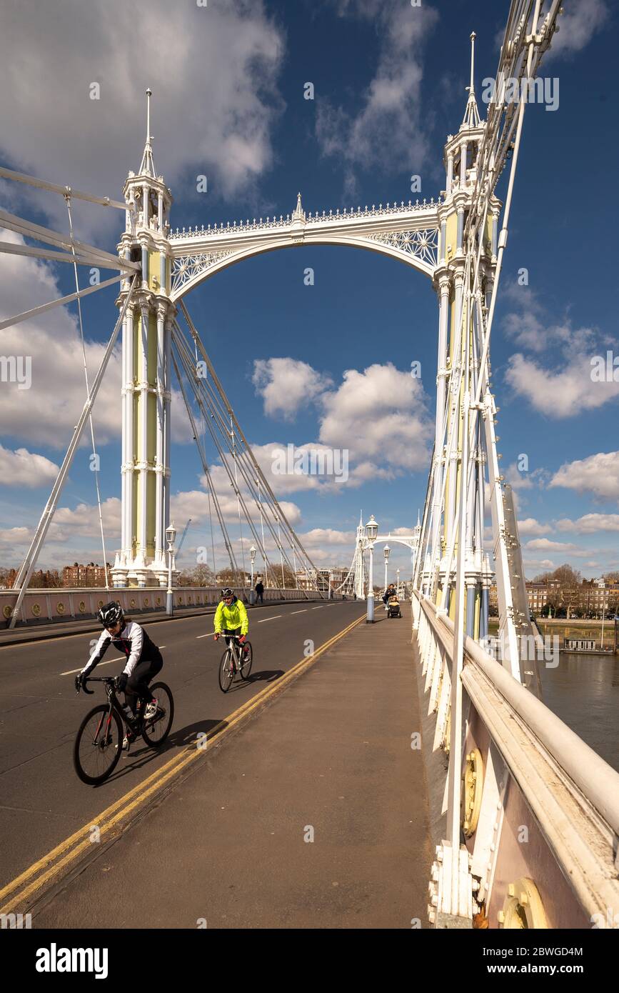 I ciclisti attraversano l'Albert Bridge sul Tamigi, Chelsea, Londra. Un edificio classificato di livello 2 e un ponte stradale unico con caratteristiche d'epoca Foto Stock