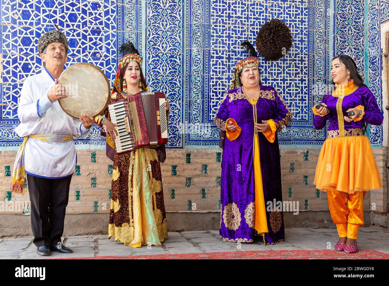 Musicisti uzbeki in abiti tradizionali che suonano strumenti musicali e cantano canzoni locali, a Khiva, Uzbekistan Foto Stock