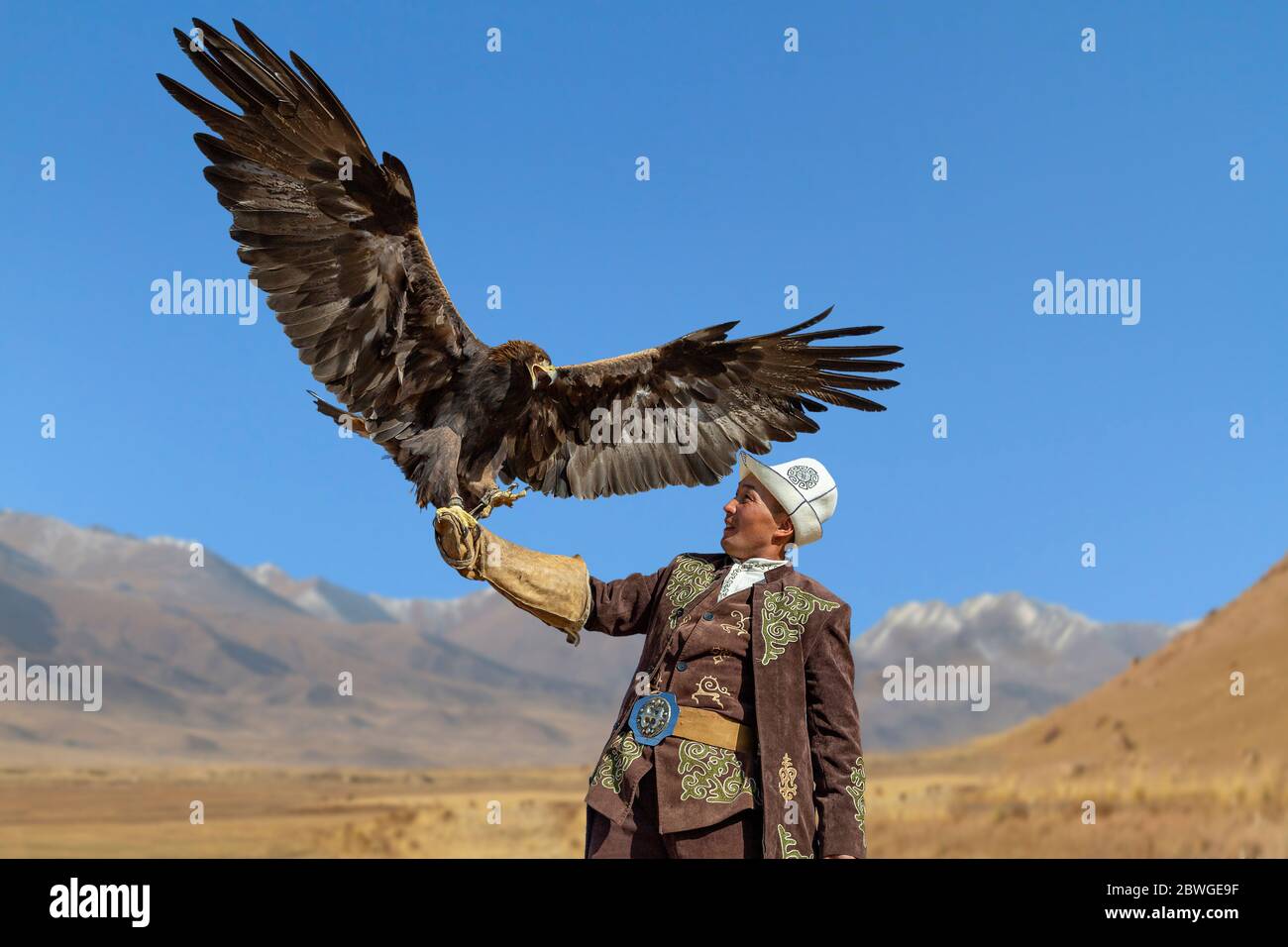 Cacciatore di aquile e la sua aquila d'oro con le ali spalancate, a Issyk Kul, Kirghizistan Foto Stock