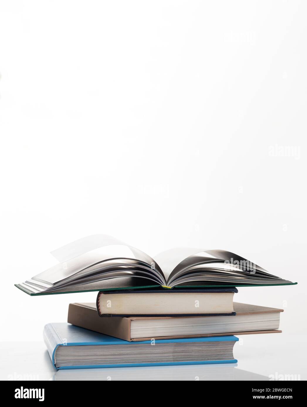 Concetto di istruzione. Pila di libri colorati chiusi e quello in alto vuoto e aperto isolato su sfondo bianco. Foto verticale, spazio per la copia. Foto Stock