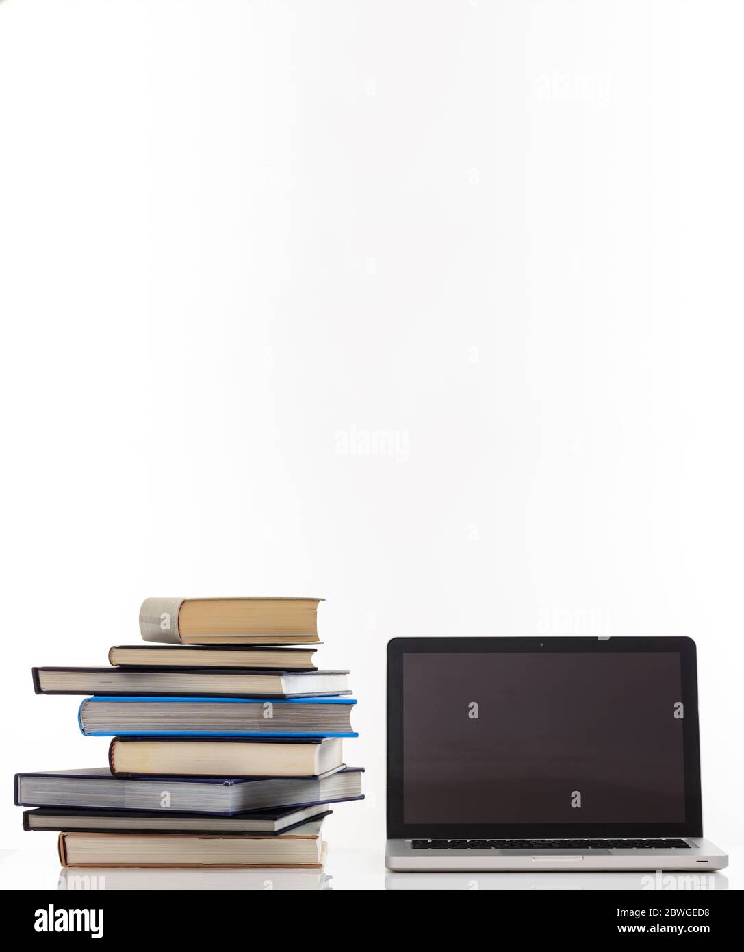 Concetto di e learning. Libri e un computer portatile aperto con schermo nero vuoto isolato su sfondo bianco. Foto verticale, spazio per la copia, modello Foto Stock