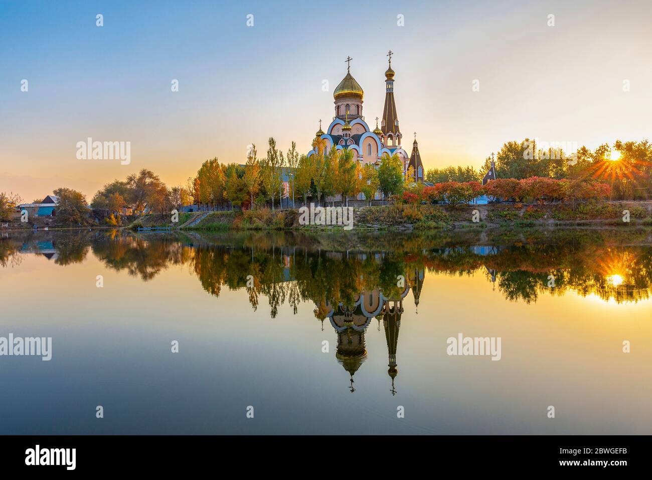 Riflessione di una chiesa ortodossa russa ad Almaty, Kazakistan, in autunno al tramonto. È conosciuta come Chiesa di esaltazione della Santa croce. Foto Stock
