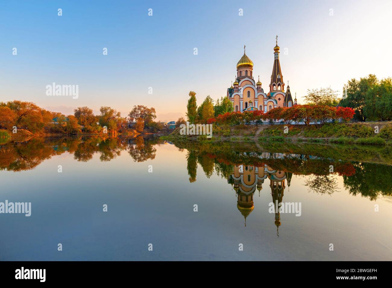 Riflessione di una chiesa ortodossa russa ad Almaty, Kazakistan, in autunno al tramonto. È conosciuta come Chiesa di esaltazione della Santa croce. Foto Stock