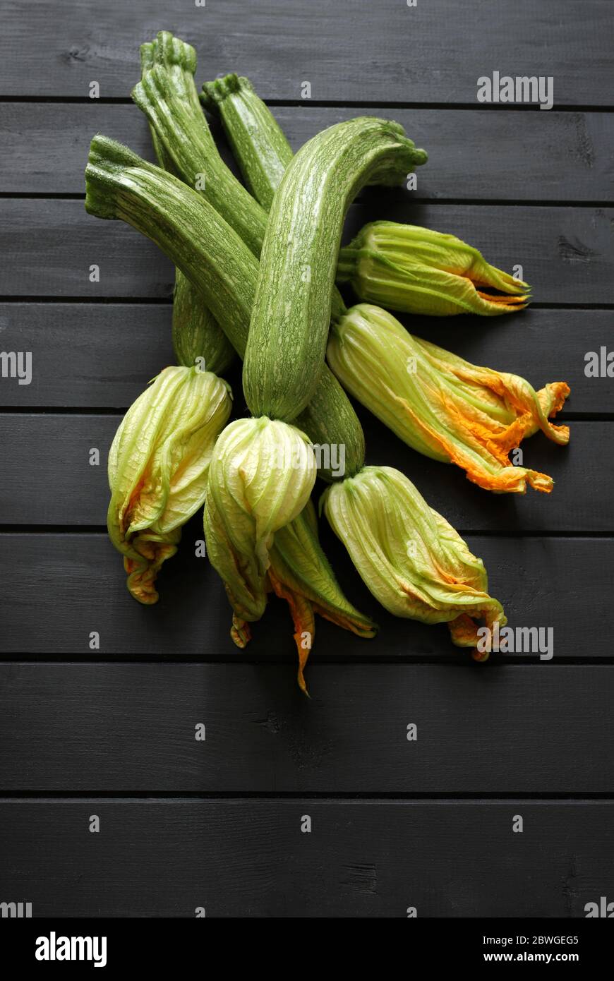 Concetto di verdure. Zucchine fresche con fiore isolato su tavola di legno. Vista dall'alto, spazio di copia. Foto Stock