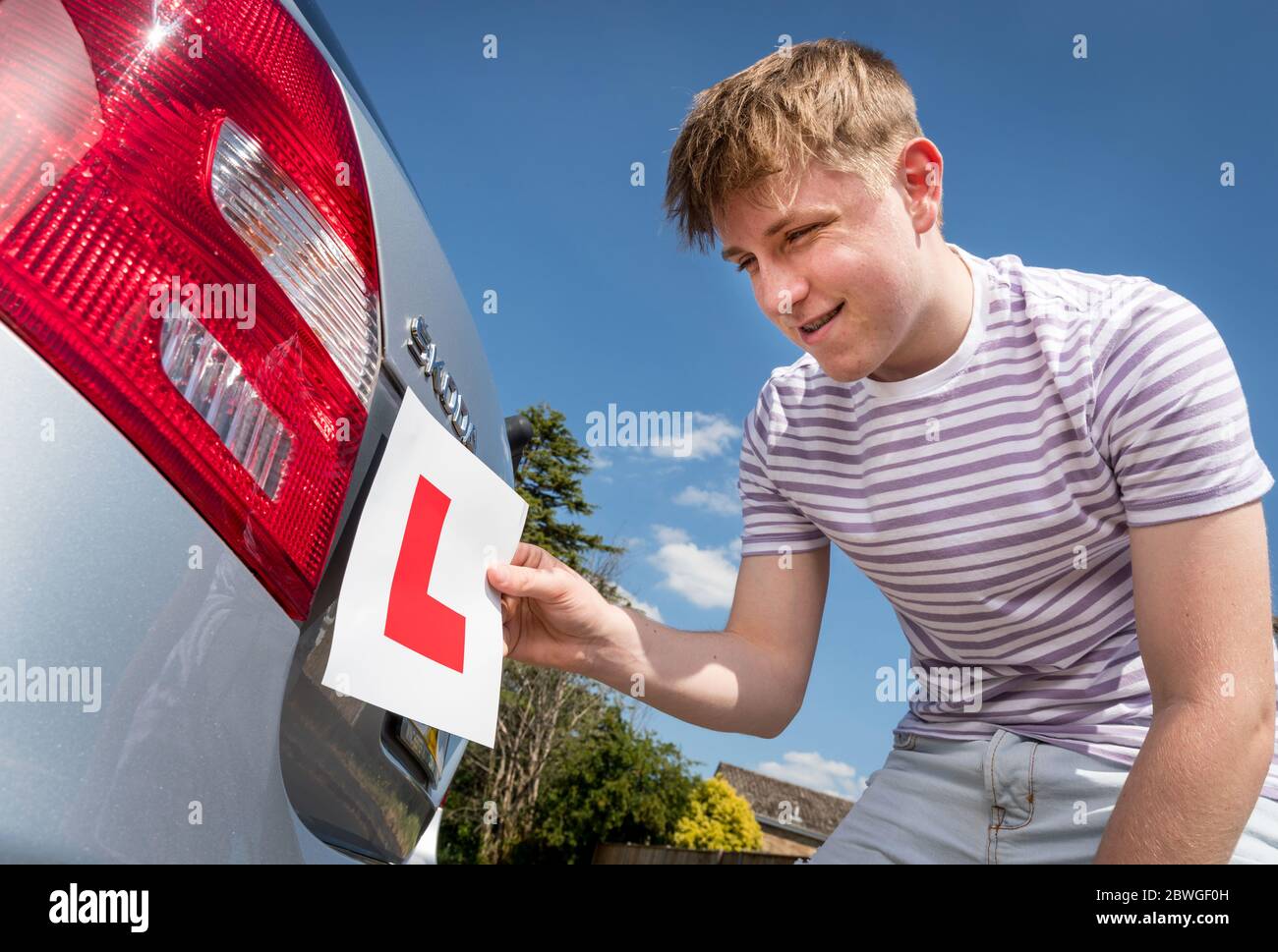 Teenage allievo driver aggiungendo le piastre L alla sua auto genitori pronto per una lezione. Foto Stock