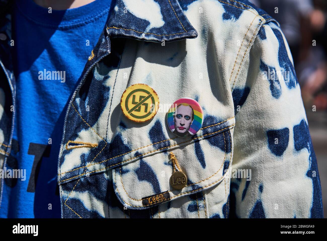 Un protestore nella città di Dublino, Irlanda con un badge antifascista e un altro badge con Vladimir Putin e un arcobaleno. Foto Stock