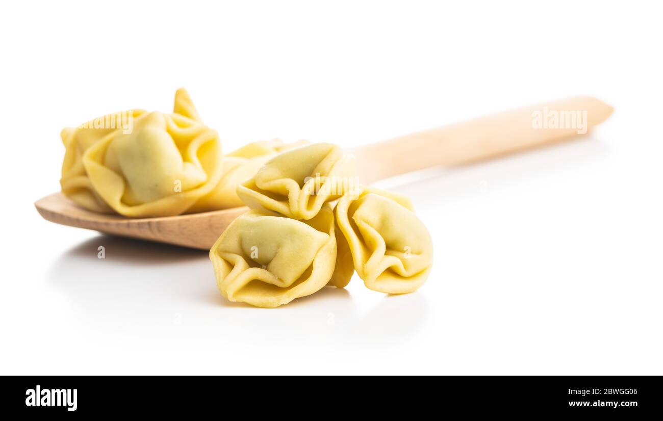 Tortellini su cucchiaio di legno. Pasta ripiena italiana isolata su sfondo bianco. Foto Stock