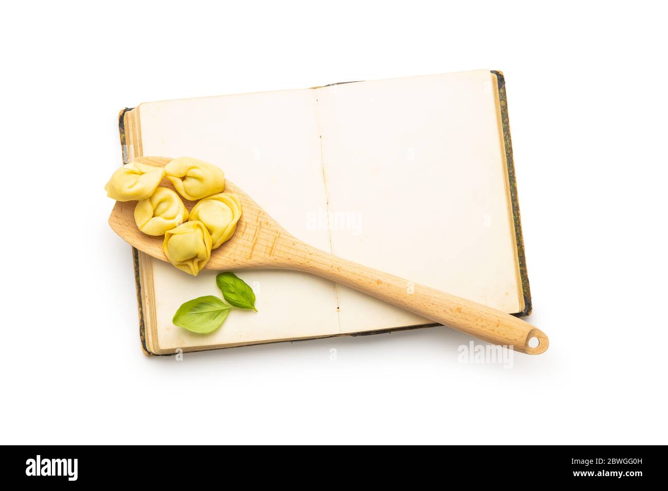 Tortellini e libro di cucina in bianco. Pasta ripiena italiana isolata su sfondo bianco. Foto Stock