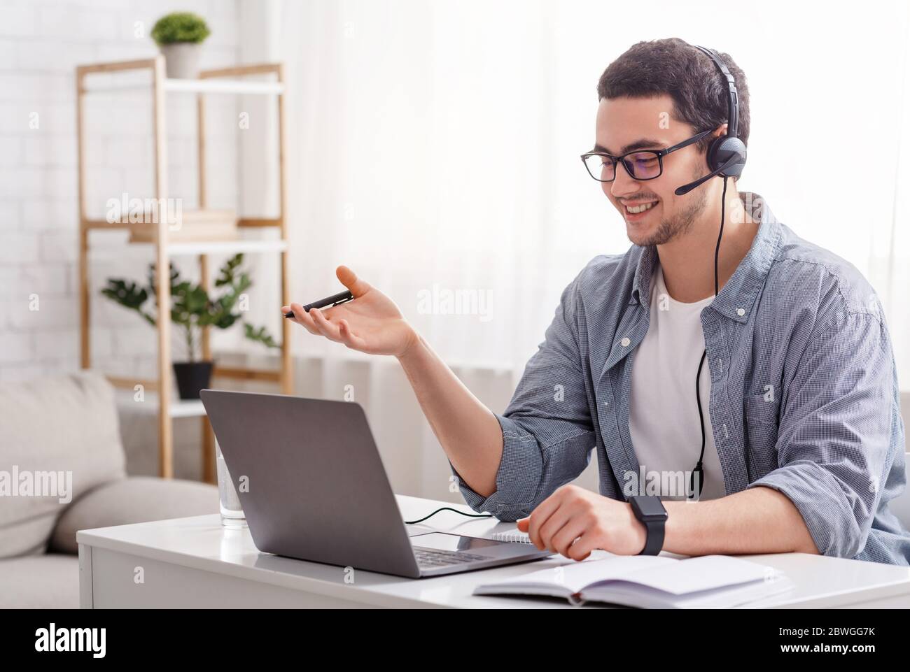 Insegnante online e lavoro da casa. Ragazzo in occhiali e cuffie che parla con lo studente Foto Stock