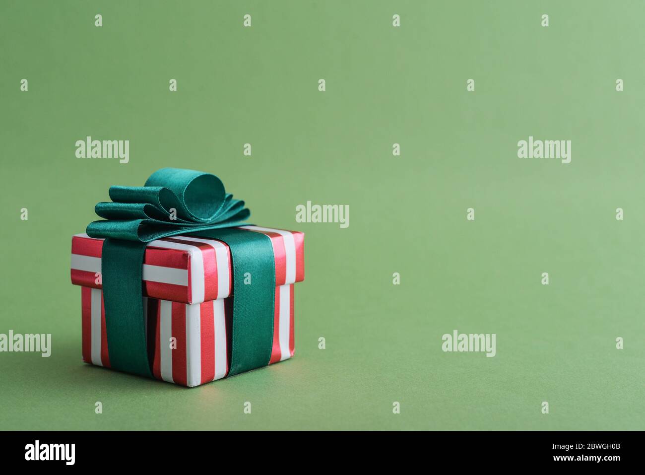 Confezione regalo a righe rosse con nastro verde su primo piano di sfondo verde Foto Stock
