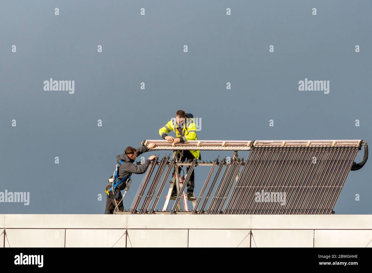 I tecnici mantengono pannelli solari fotovoltaici sul tetto dell'edificio per uffici a Killarney in Irlanda come concetto di cambiamento climatico. Foto Stock