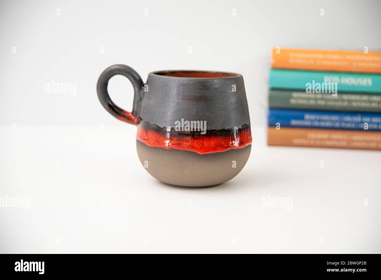 tazza da caffè in ceramica colorata fatta a mano con libri sul tavolo Foto Stock