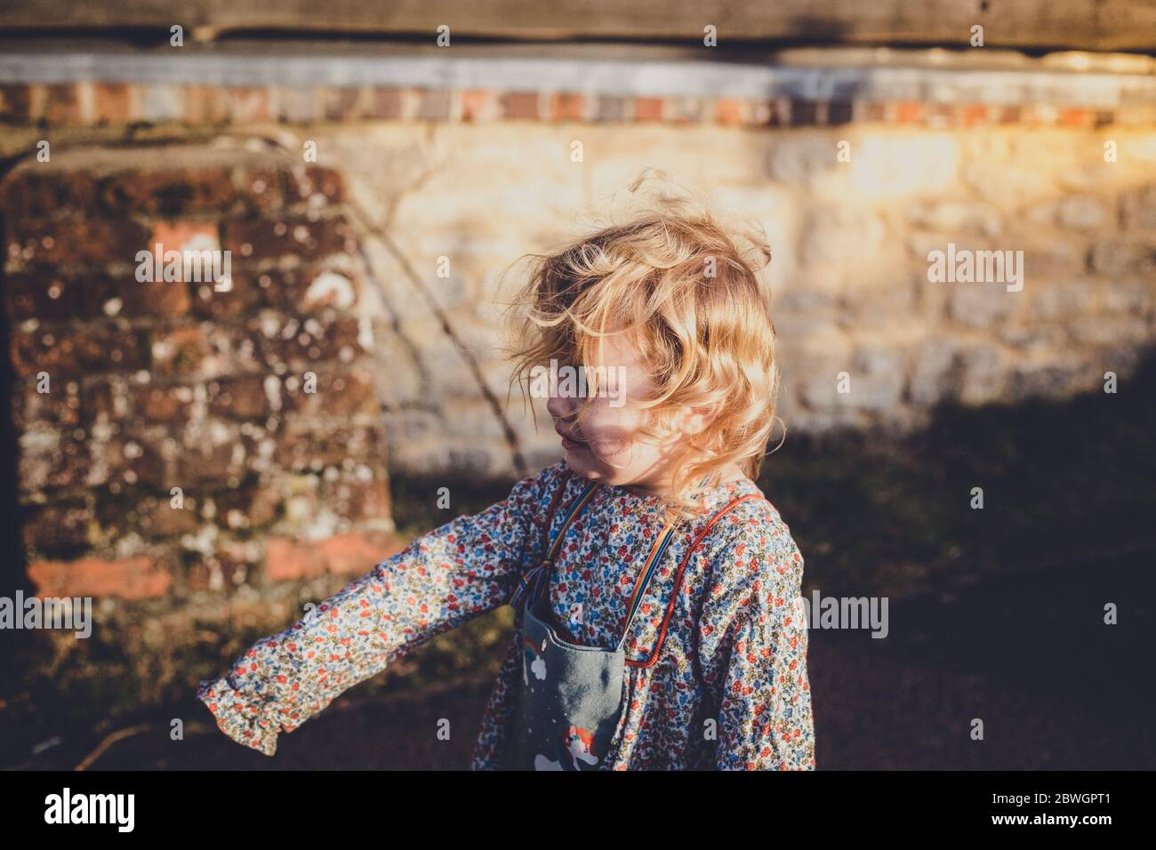 Bambina con capelli ricci che soffia nel vento Foto stock - Alamy