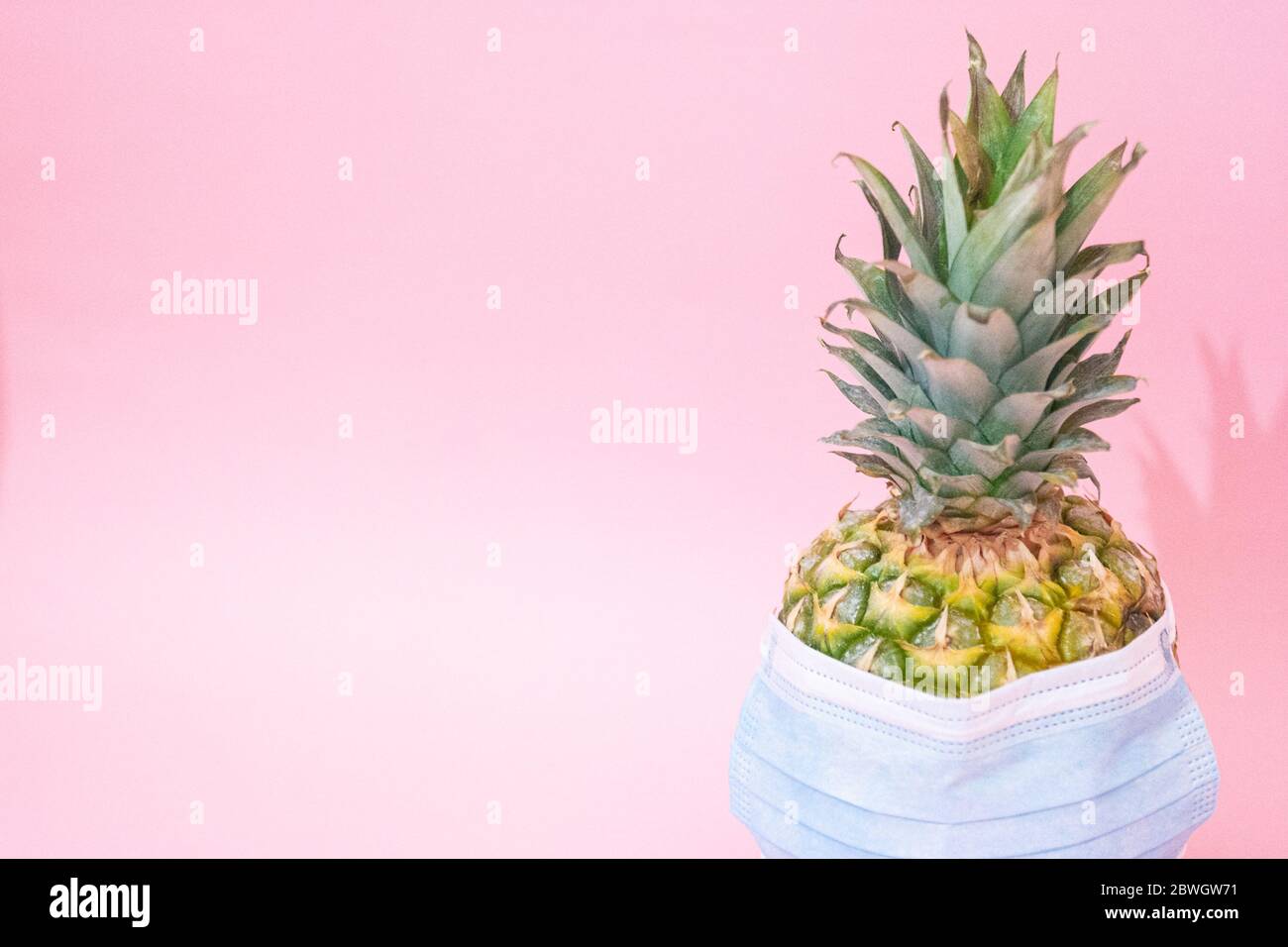 Maschera medica blu contro l'influenza stagionale su un ananas. Concetto minimo Foto Stock