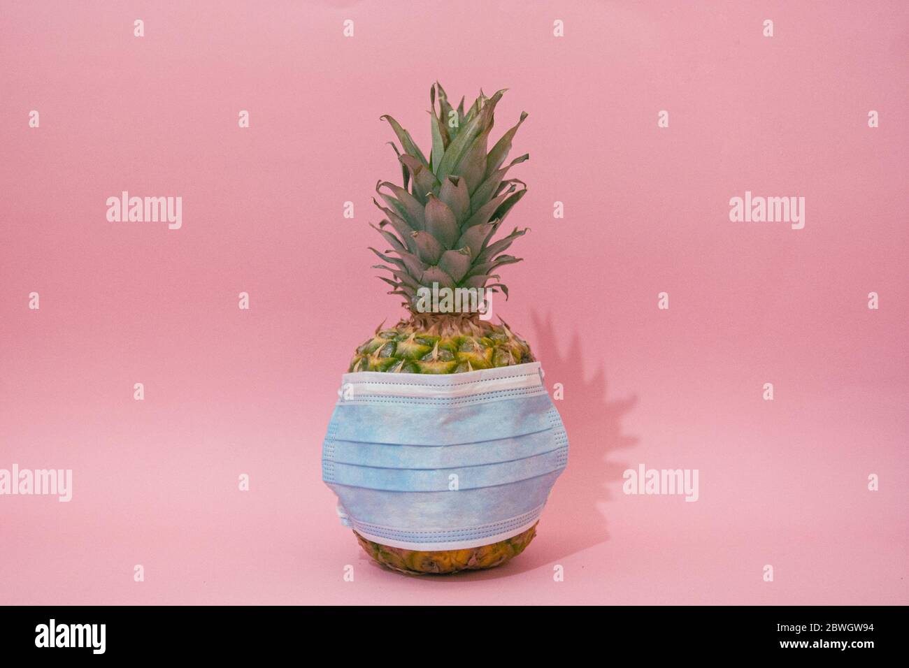 Maschera medica blu contro l'influenza stagionale su un ananas. Concetto minimo Foto Stock
