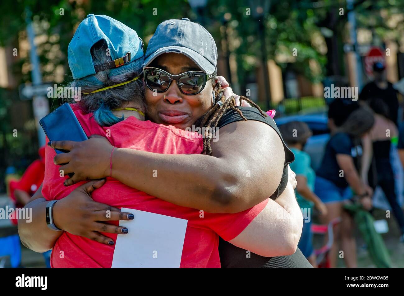 Una donna afroamericana e una donna caucasica si abbracciano durante una veglia per George Floyd a Cathedral Square, 31 maggio 2020, a Mobile, Alabama. Foto Stock