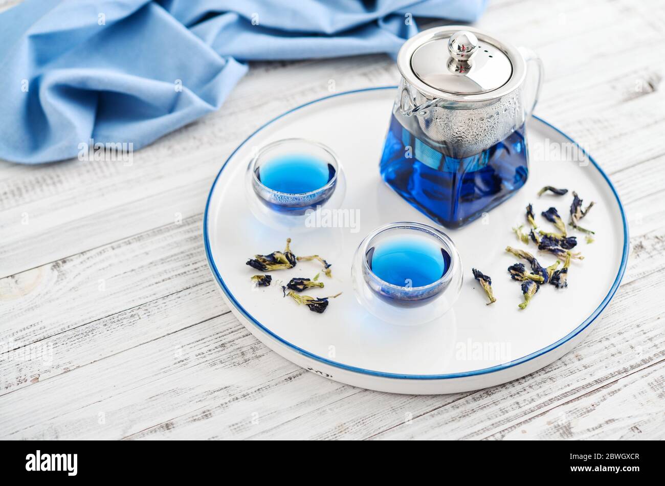 Due bicchieri di tè blu Anchan con teiera su sfondo bianco di legno Foto Stock