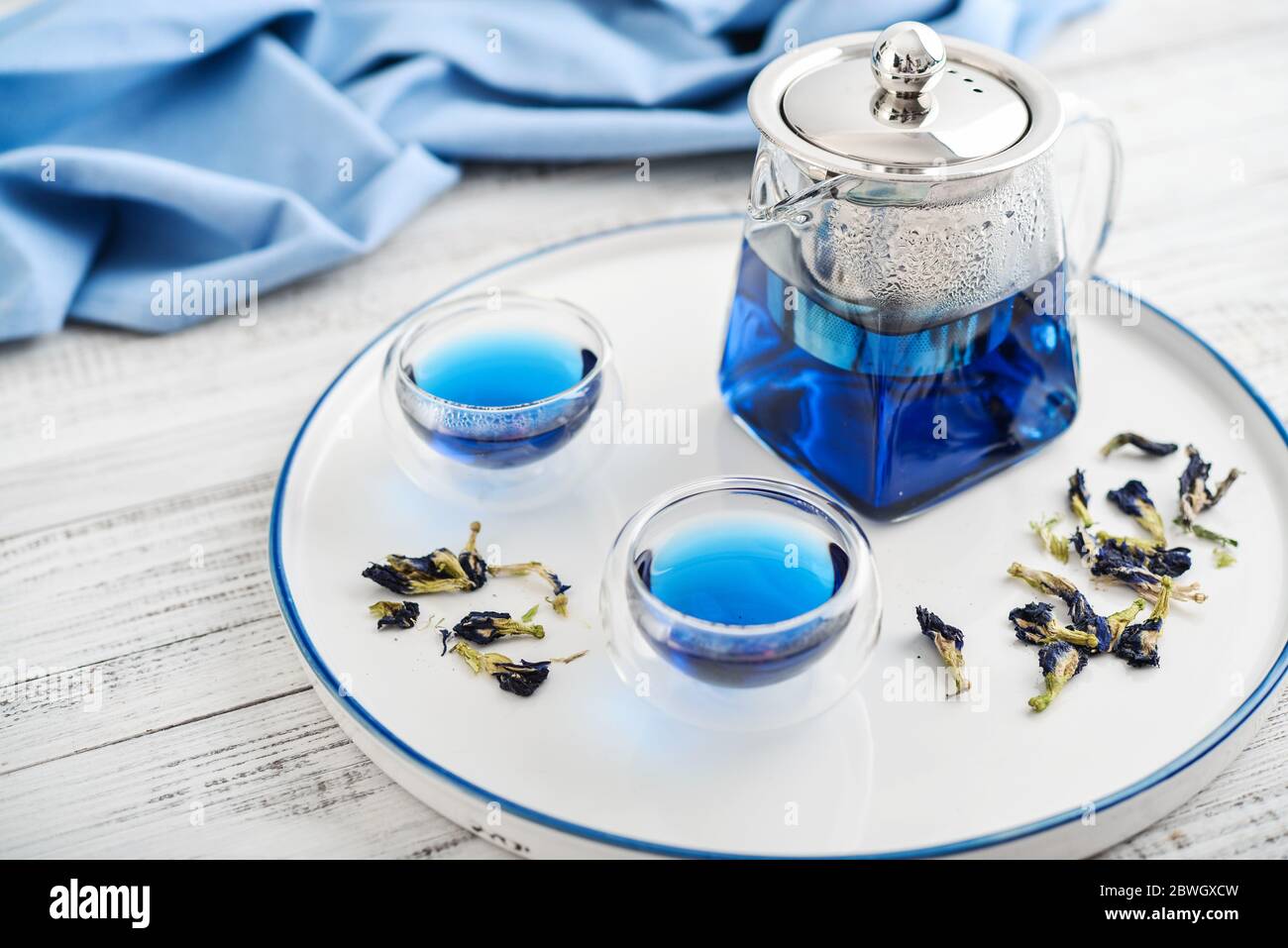 Due bicchieri di tè blu Anchan con teiera su sfondo bianco di legno Foto Stock