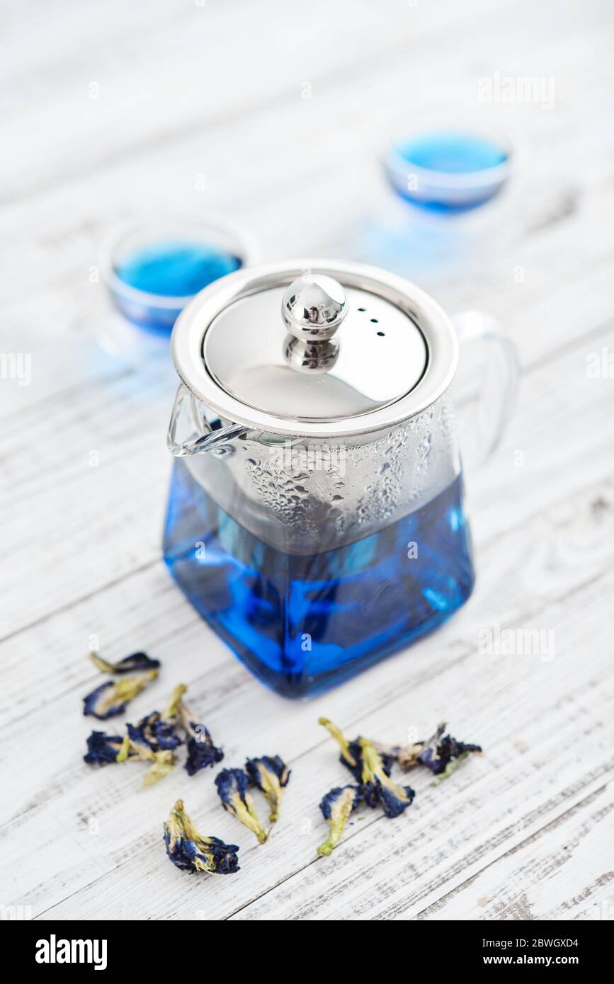 Due bicchieri di tè blu Anchan con teiera su sfondo bianco di legno Foto Stock
